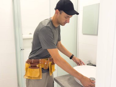 Banyoda lavabo tamir eden genç bir tesisatçı. Yüksek kalite fotoğraf