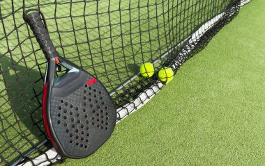 Yeşil sahada, açık havada, Padel tenis raketinin yanındaki yerde, doğal ışıklandırmalı sarı topların en üst görüntüsü. Kürek bir raket oyunudur. Profesyonel spor konsepti. Yüksek kalite fotoğraf