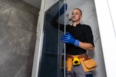 Duş kabininde çalışan profesyonel bir tamirci. Yüksek kalite fotoğraf