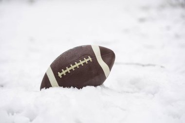 a football covered with snow and laying in the snow. High quality photo clipart