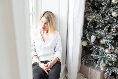  Genç ve güzel bir kadın Noel ağacının yanında. Şatafatlı bir iç mekanda makyajlı güzel, şehvetli bir yeni yıl kadını. Yüksek kalite fotoğraf