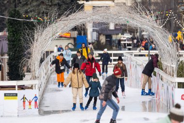 KYIV, UKRAINE - 1 January, 2023: Ice-skating people. People have fun in ice arena at the city ice rink. New Years holidays in city Kyiv