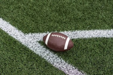 Sahadaki çimen futbol sahasında oturan bir Amerikan futbolunun yakın görüntüsü. Genel spor imajı. Yüksek kalite fotoğraf