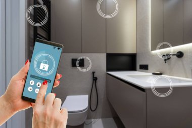 Akıllı ev teknolojisi, akıllı telefon uygulamasındaki IoT İnternet arayüzü modern apartman içindeki nesnelere bağlı ekran, uzaktan kumanda olarak kadın tutucu aygıtı.