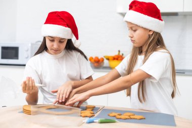 İki kız kardeş Noel kurabiyeleri yaptıktan sonra mutfakta oynuyorlar, masaya ve yüzlerine un çiziyorlar. Noel, yeni yıl konsepti. Yüksek kalite fotoğraf