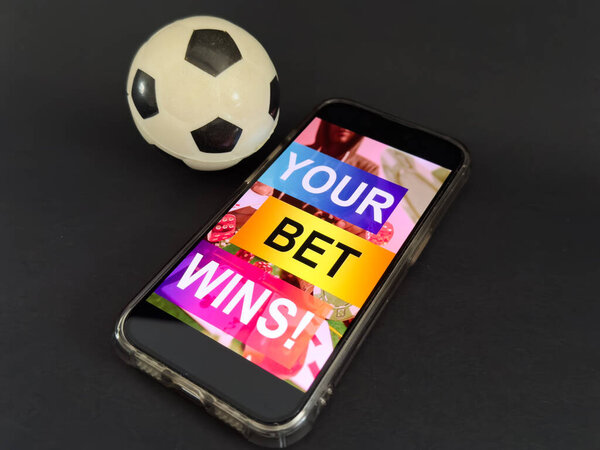 Smartphone with gambling mobile application and soccer ball close-up. Sport and betting concept. High quality photo
