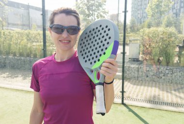 Açık alanda tenis raketi ve topu olan atletik bir kadına yakın durun. Yüksek kalite fotoğraf