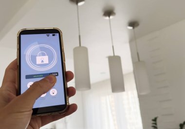 Akıllı ev otomasyon uygulaması arka planda iç mekan olan kadın eliyle akıllı telefondan tutulmuş. Yüksek kalite fotoğraf