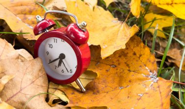 Bokeh ile birlikte sarı ahşap zemin üzerinde klasik çalar saat ve akçaağaç yaprakları. Sonbahar sezonu imajı. Yüksek kalite fotoğraf