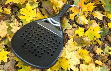 Ağ arkasında yeşil bir kort çimenliği üzerinde siyah bir padel raketinin üst görüntüsü. Kürek bir raket oyunudur. Profesyonel spor konsepti, metin için boşluk. Yüksek kalite fotoğraf