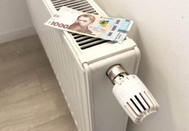 New thermostat with cash on a radiator heating at home. Expensive heating costs symbolic image. High quality photo clipart