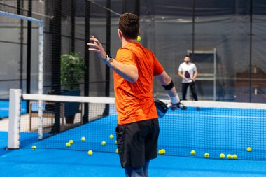 Padel oyuncusunun Padel 'i kapalı bir sahada, kalenin arkasında oynadığı bilinmiyor. Yüksek kalite fotoğraf