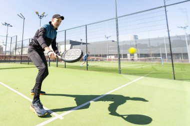 Ağ arkasında yeşil çim bir padel kortunda padel oynayan adam. Yüksek kalite fotoğraf