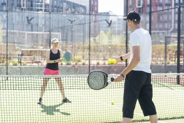  Genç bir kadın açık hava tenis kortunda partneriyle Padel Tenis oynuyor. Yüksek kalite fotoğraf