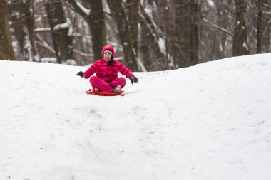 Çocukluk, kızak ve sezon konsepti. Mutlu küçük kız kışın açık havada kızakla kayıyor. Yüksek kalite fotoğraf