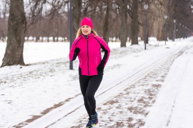 Parkta kış koşusu: mutlu kadın koşucu karda koşuyor, açık hava sporu ve fitness konsepti. Yüksek kalite fotoğraf