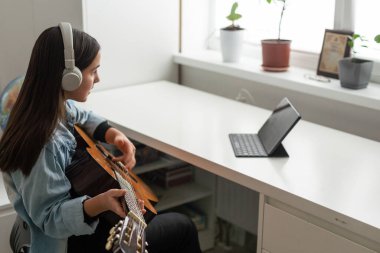 Müzik dersleri sırasında gitar çalan gülümseyen genç öğrencinin portresi. Yüksek kalite fotoğraf