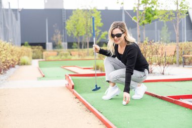 Woman playing mini golf at course. Summer sport and leisure activity. High quality photo clipart