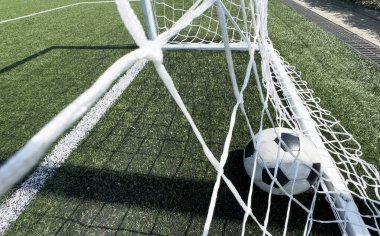 Açık hava futbol stadyumunda suni, parlak ve koyu yeşil çimlerde futbol topu. Yüksek kalite fotoğraf