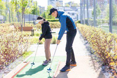 Genç ve yakışıklı bir baba küçük kızına golf oynamayı öğretiyor. Yüksek kalite fotoğraf