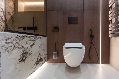 Duvar asılmış tuvalet. Gri duvardaki beyaz tuvalet. Yerdeki fayanslar ahşabı taklit eder. Yüksek kalite fotoğraf