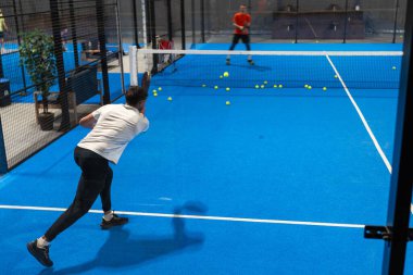 Padel oyuncusunun Padel 'i kapalı bir sahada, kalenin arkasında oynadığı bilinmiyor. Yüksek kalite fotoğraf