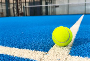 Açık havada mavi kortta kürek ağının arkasında sarı top var. Padel tenisi bir raket oyunudur. Profesyonel spor konsepti. Yüksek kalite fotoğraf