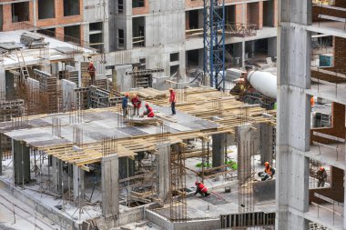 İnşaat işçileri çimento çerçevelerinin montajında işbirliği yapıyorlar. Yüksek kalite fotoğraf