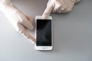 Elinde mavi koruyucu eldivenle beyaz arka planda izole edilmiş boş bir akıllı telefon. Bir metin için boşluk kopyala