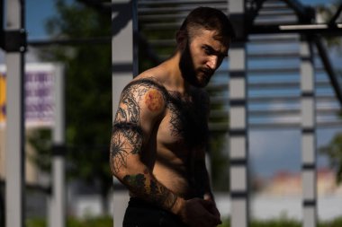 Genç adam parkta egzersiz makinesinin üzerinde antrenman yapıyor..