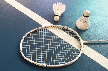 Krem beyazı badminton servis aleti ve kapalı badminton kortunda yerde neon ışıklı raket, kopyalama alanı, yumuşak ve seçici odaklanma. Yüksek kalite fotoğraf