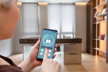 Akıllı ev otomasyon uygulaması arka planda iç mekan olan kadın eliyle akıllı telefondan tutulmuş. Yüksek kalite fotoğraf