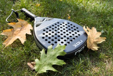 Kyiv, Ukrayna, 29 Eylül 2024, ağların arkasındaki yeşil çimlerin üzerinde siyah padel raket nox. Kürek bir raket oyunudur. Yüksek kalite fotoğraf