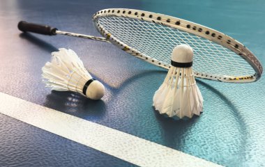 Krem beyazı badminton servis aleti ve kapalı badminton kortunda yerde neon ışıklı raket, kopyalama alanı, yumuşak ve seçici odaklanma. Yüksek kalite fotoğraf