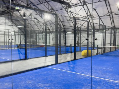 Boş raket tenis kortu, kapalı bir barakanın ışıkları açık ve oyuncuları yok. Yüksek kalite fotoğraf