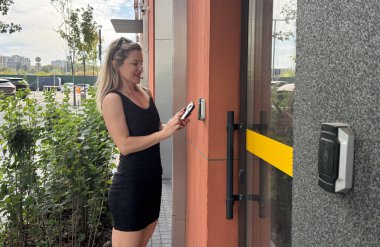 Bina girişinde zili çalan mutlu kadın. Dahili telefon kullanılıyor. Yüksek kalite fotoğraf