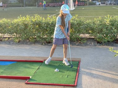 Küçük aktif bir çocuk, küçük tatlı bir kız, minyatür golf oynuyor, açık havada güneşli bir yaz tatili geçiriyor. Yüksek kalite fotoğraf