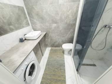 Gri beton duvarları, gri mermer zemini, su dolu beyaz küveti olan minimalist otel banyosu. Yüksek kalite fotoğraf