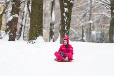 Kızak süren bir kız, karda dışarıda oynayan. Yüksek kalite fotoğraf