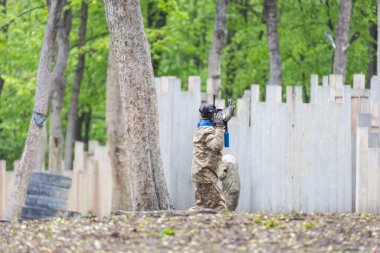 Paintball oyunu. Silahlı oyuncular boya topu atıyorlar. Çocuk parkındaki adamlar. Kamuflajlı ve maskeli adamlar kavga ediyor. Yüksek kalite fotoğraf