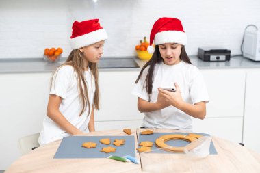 İki kız kardeş Noel kurabiyeleri yaptıktan sonra mutfakta oynuyorlar, masaya ve yüzlerine un çiziyorlar. Noel, yeni yıl konsepti. Yüksek kalite fotoğraf