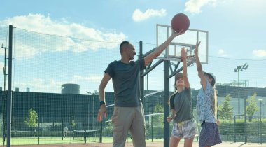 Bir spor ailesi basketbol oynar, genç bir baba, kızlar basketbol sahasında boş zaman geçirir, sağlıklı bir hayat sürer, genç bir kız top atar. Yüksek kalite fotoğraf