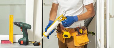 Bir çerçeve eve plastik montajı, inşaatçı bir tornavidayla pencere çerçevesini yamaçlara vidalar. yakın plan