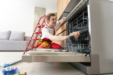 Tamirci mutfaktaki bulaşıkçıyı kontrol ediyor..