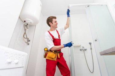 Tesisatçı banyoya duş kabini kuruyor..