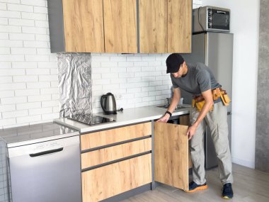 Marangoz, mutfak rafının montajını duvarda tamamlıyor. Yüksek kalite fotoğraf