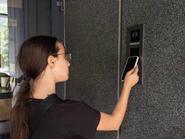 Genç kız evdeki güvenlik sistemlerini dijital kapı ile kilitlemek için telefon taraması kullanıyor. Yüksek kalite fotoğraf