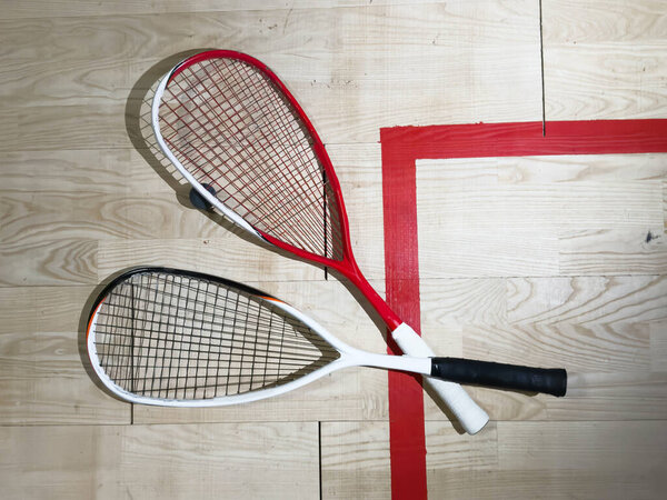 Two rackets and two squash balls lie on the parquet floor. Horizontal photo. High quality photo