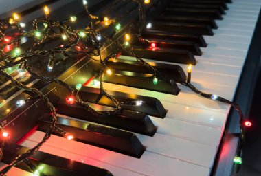 Piyano klavyesi ve Noel ağacı aydınlatmaları. Canlı renkler, tatil konsepti. Yüksek kalite fotoğraf