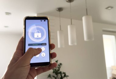 Akıllı ev, ev otomasyonu, uygulama simgeli aygıt. Adam akıllı telefonunu akıllı uygulama ile evinin ışıklarını kontrol etmek için kullanıyor. Yüksek kalite fotoğraf
